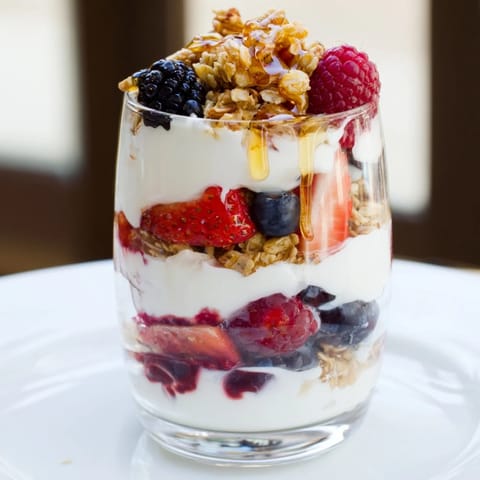 This layered Berry Parfait features juicy red strawberries, and blueberries, perfect for breakfast.