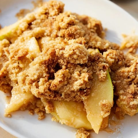 Warm apple crumble bubbling, golden crust, perfect dessert served with vanilla ice cream.