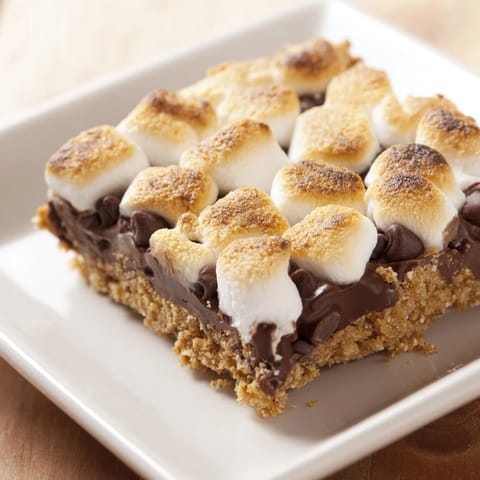 Gooey Smores bars featuring buttery graham cracker base, topped with melted chocolate and golden marshmallows.