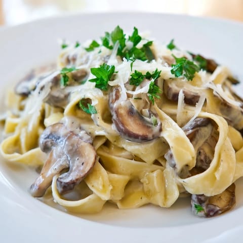 Creamy mushroom alfredo tossed with fettuccine, featuring sautéed cremini mushrooms and garlic in a velvety sauce.