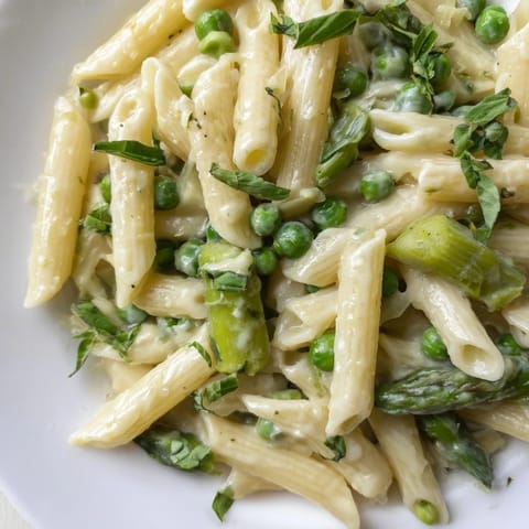 Hearty penne pasta coated in a silky garlic-Parmesan cream sauce, tossed with crisp-tender spring vegetables and finished with a squeeze of lemon juice and fresh parsley.
