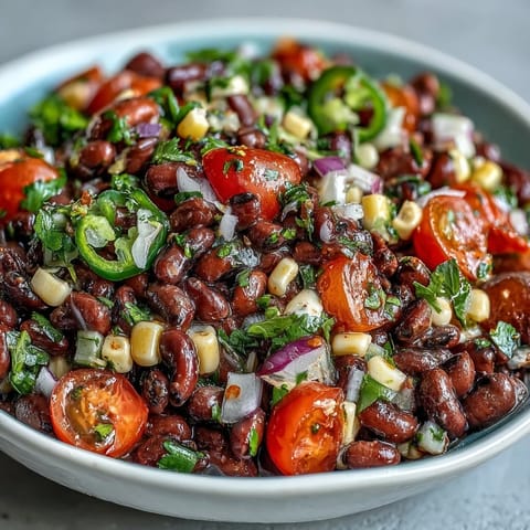 Colorful Cowboy Caviar in a white bowl, featuring black beans, corn, diced peppers, and cilantro tossed in zesty lime dressing.