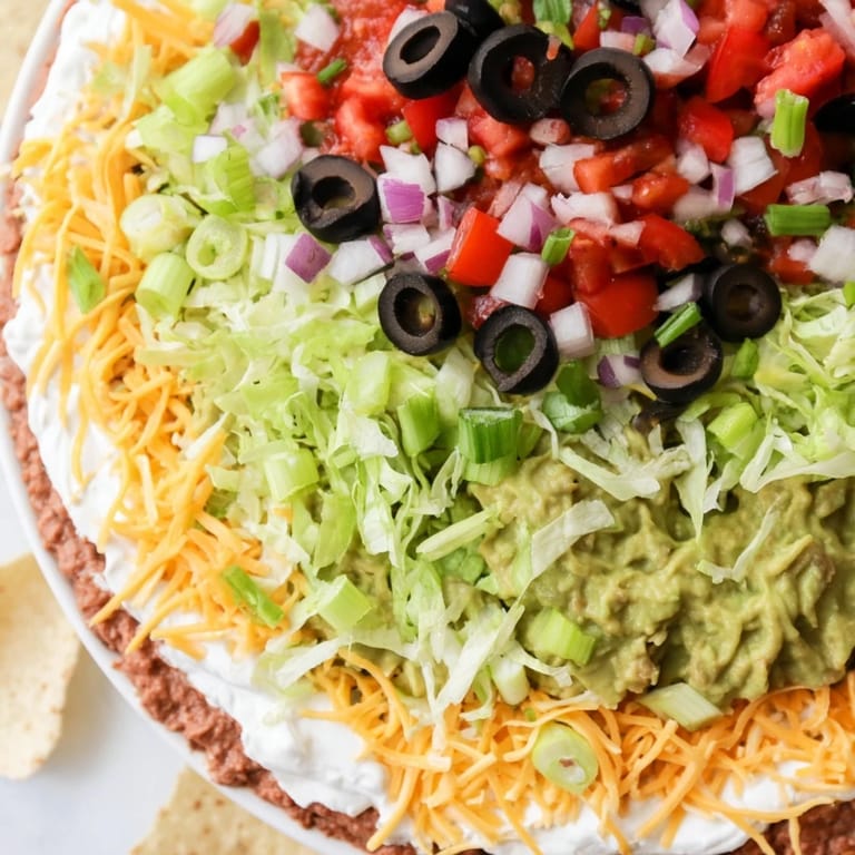 A refreshing view of a chilled Seven-Layer Dip: refried beans, guacamole, and toppings ready to eat.