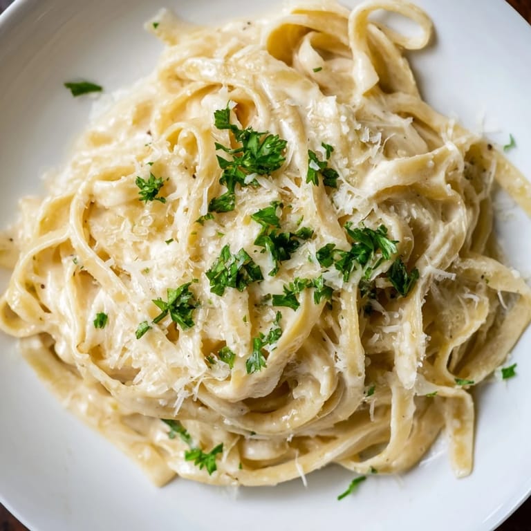 Steaming Roasted Garlic Cream Pasta garnished with fresh parsley and extra Parmesan cheese, ready to enjoy.