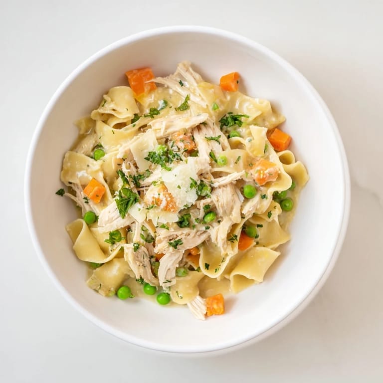 A close-up of Spring Chicken Noodle Skillet, featuring juicy chicken, bright peas, and carrots tossed in a velvety Parmesan sauce.