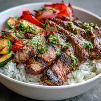 Vibrant Grilled Steak Bowl with fluffy rice and caramelized roasted vegetables on a white plate.