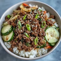 A colorful Korean ground beef bowl with savory beef over jasmine rice and tangy pickled vegetables.  