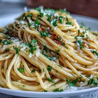 Creamy lemon butter pasta with fresh zest and Parmesan, twirled on a fork against a rustic kitchen backdrop.