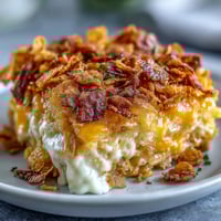Cheesy hash brown casserole with golden cornflake topping, bubbling with creamy cheddar and sour cream.