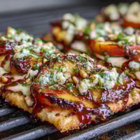 Grilled flatbread with juicy peaches, creamy Brie, and smoky BBQ sauce, topped with fresh herbs and red onion.